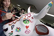 Una artista pinta una vaca durante la presentación de la 'Cow Parade' madrileña. (Foto: EFE)